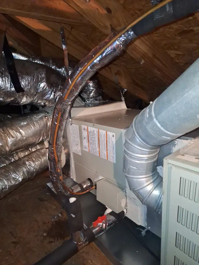 Attic air handler with a flue pipe, an insulated line set and a condensate trap