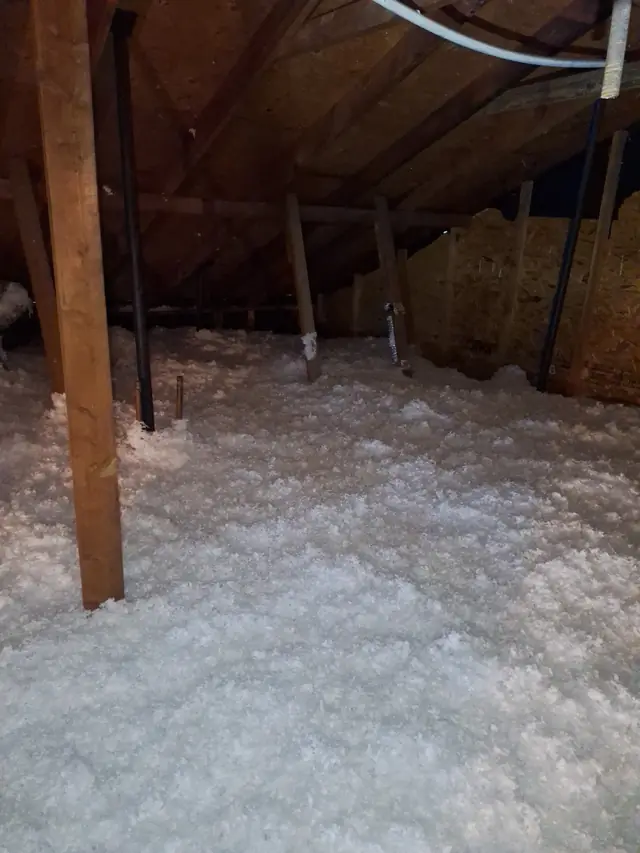 Fresh blown-in insulation spread level across the attic joists